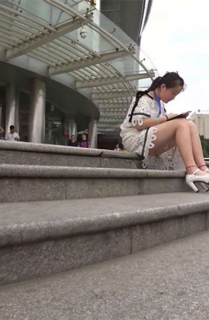 街拍专心玩手机的白色高跟白色蕾丝连衣短裙美眉