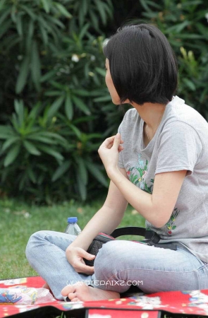 草地上盘腿而坐的短发牛仔少妇